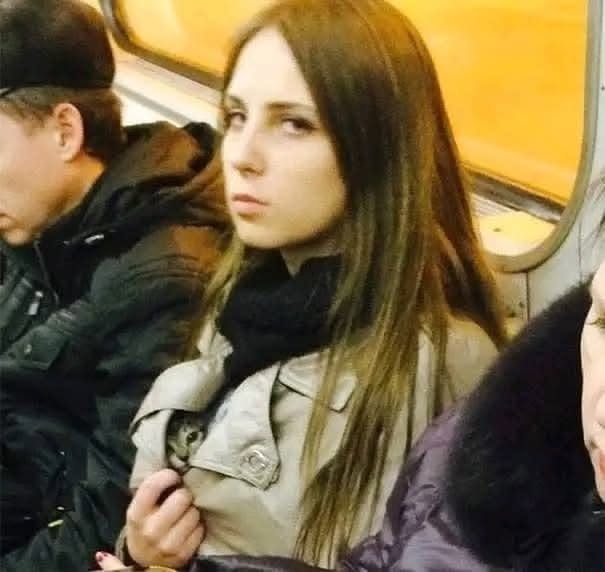 Nie je možné identifikovať osobu na fotografii. Žena v metre s mačkou skrytou v kabáte.