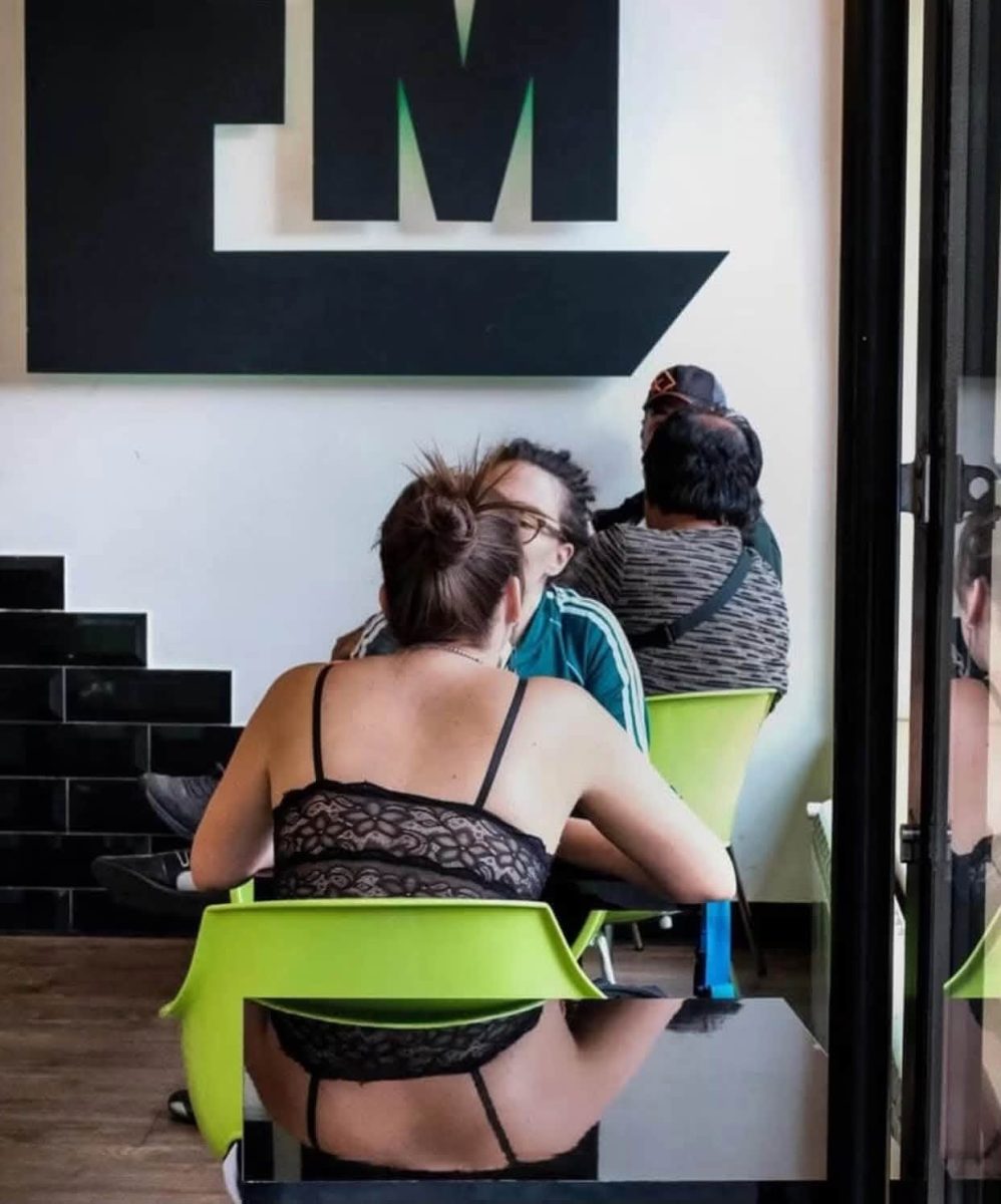 Žena sedí pri stole v kaviarni, odraz v lesklom povrchu stola vytvára zaujímavý vizuálny efekt.