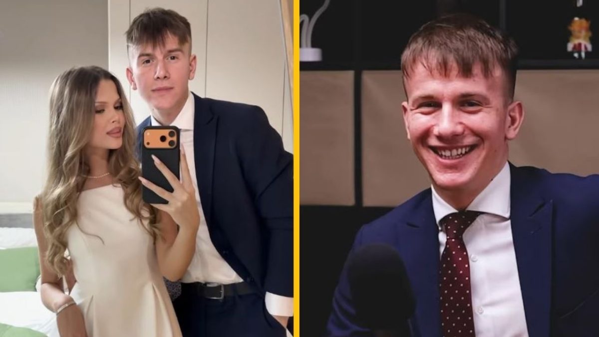 Dvojica v elegantnom oblečení si robí selfie; muž s úsmevom pred mikrofónom.