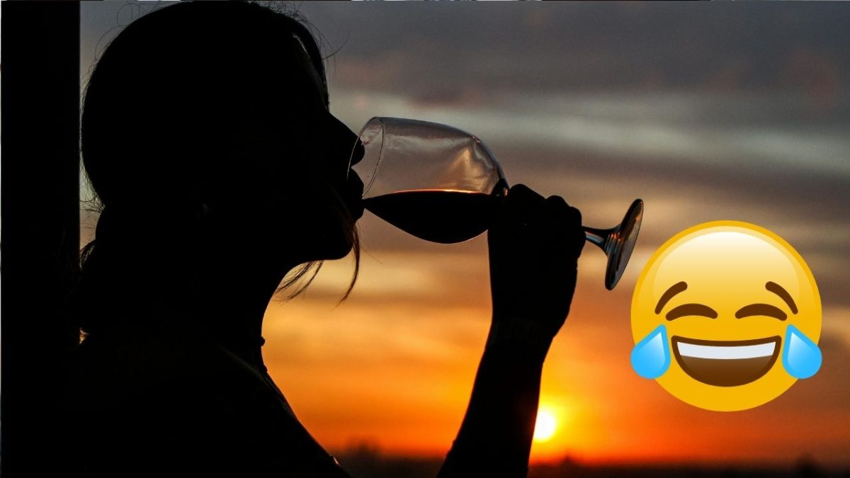 Osoba si vychutnáva pohár vína pri západe slnka, s obrázkom smejúceho sa emotikonu.