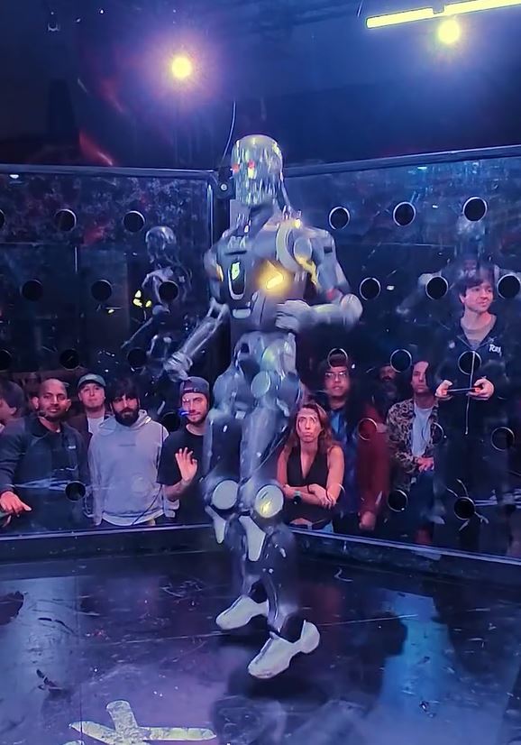 Robot tancuje pred davom ľudí v osvetlenej aréne plnej reflektorov a technológie.