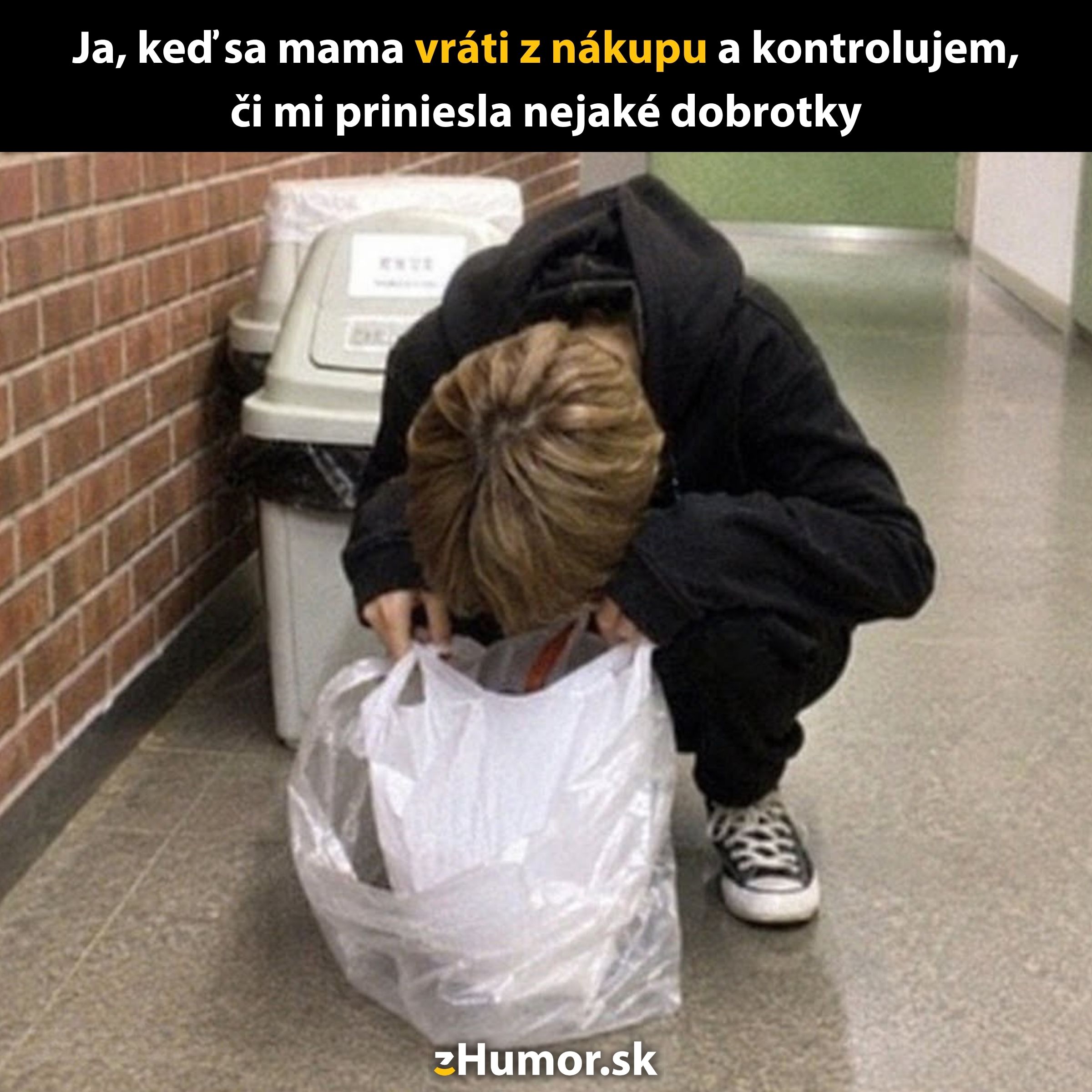 Osoba kontroluje tašku po nákupe, zohnutá oproti stene, zvedavo hľadá dobroty prinesené z obchodu.