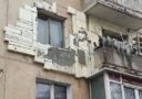 Fasáda bytového domu s rôznymi povrchmi a svetlými obdĺžnikovými dielmi okolo okien.