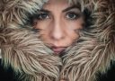 a woman wearing a fur coat with a hood over her face