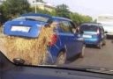 Modré auto so slameným nákladom vyčnievajúcim z kufra stojace v premávke na ceste.