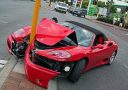 Červené športové auto nabúralo do pouličnej lampy na križovatke, poškodená predná časť vozidla.