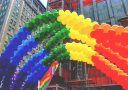Pestrofarebné balónové oblúky nad mestskou ulicou počas Pride festivalu.