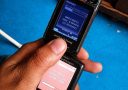 Starý Sony Ericsson telefón sťahuje súbor, retro technológia na modrom pozadí s textom Keď vieš, tak vieš.
