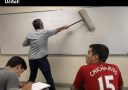 Učiteľ maže tabuľu valčekom, zatiaľ čo študenti zapisujú poznámky. Text vtipne zachytáva situáciu v triede.