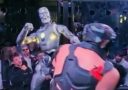 Robot a človek v ringu bojujú pred divákmi. Zápas technológie proti sile.